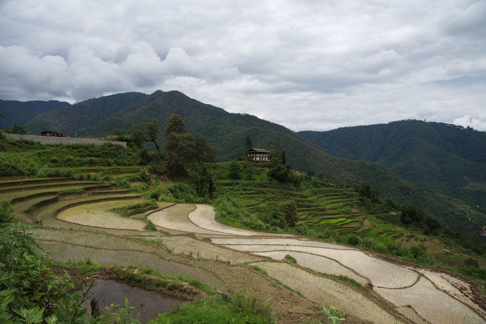 green grass field near mountain under white clouds during daytime