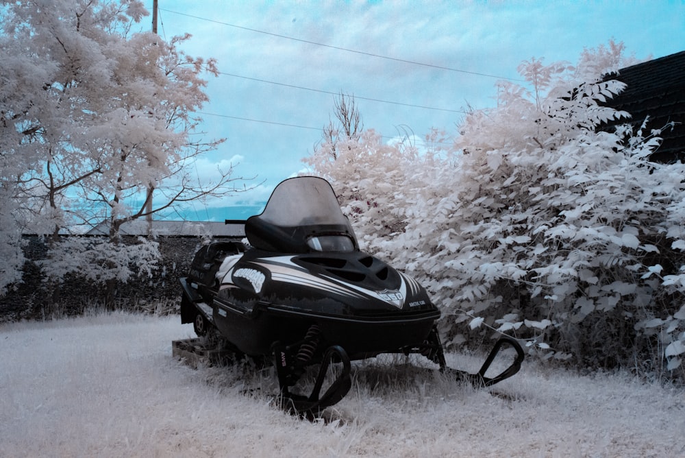 uma moto de neve estacionada na neve ao lado de uma árvore