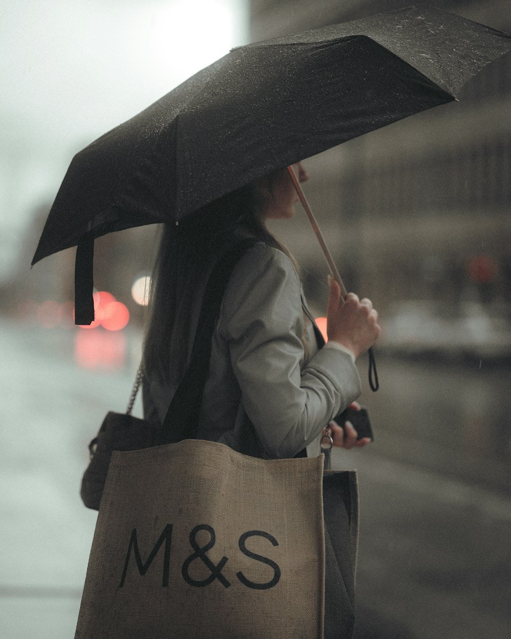 person in black coat holding umbrella