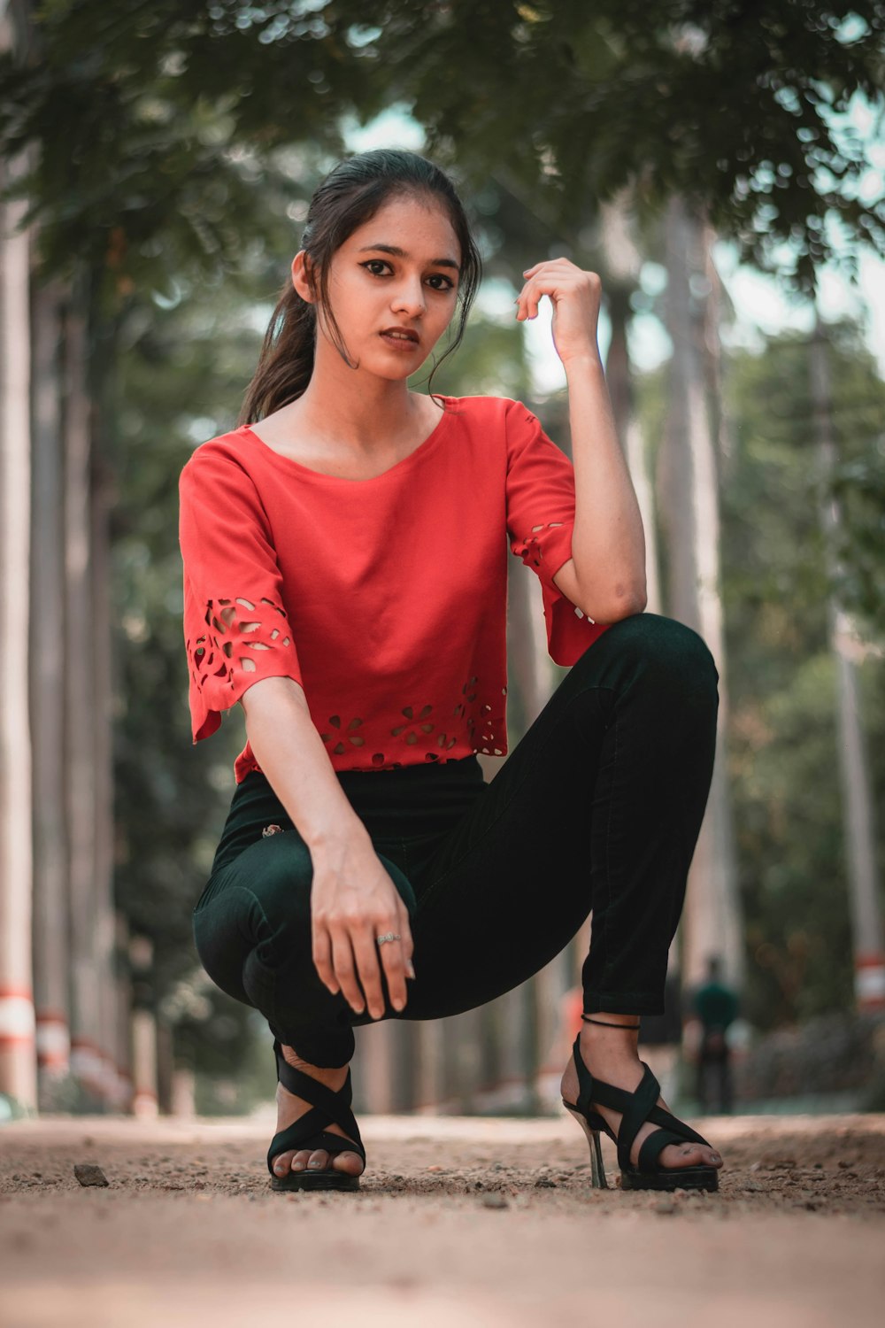 woman in red long sleeve shirt and black pants sitting on brown wooden seat
