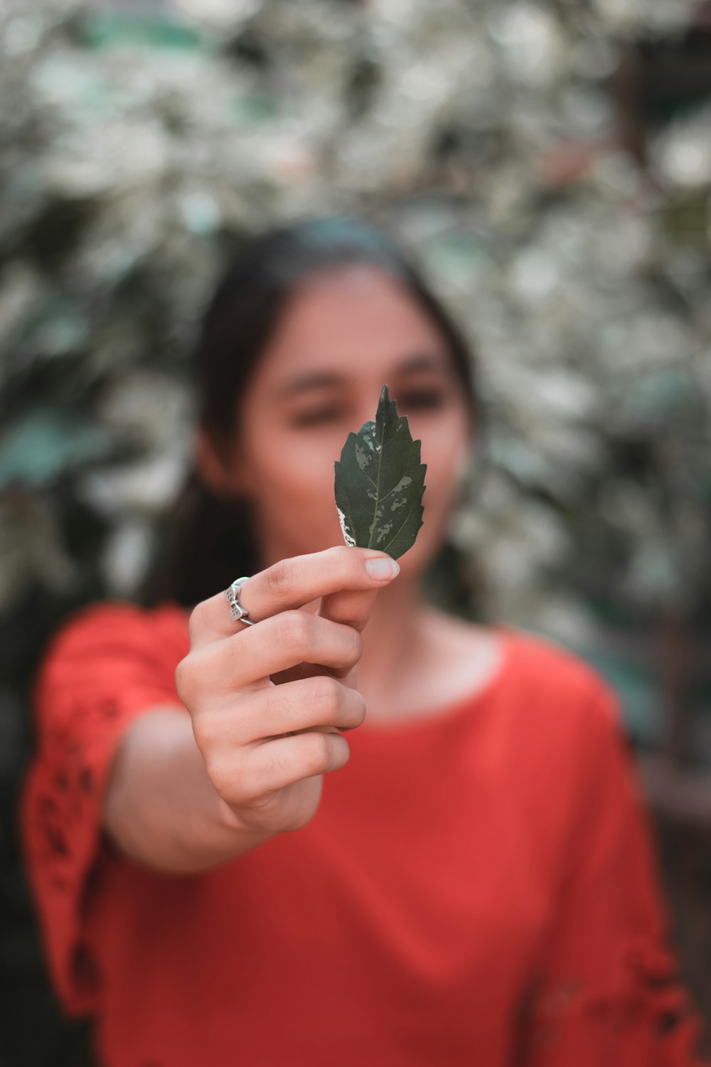 a woman holding a leaf in front of her face