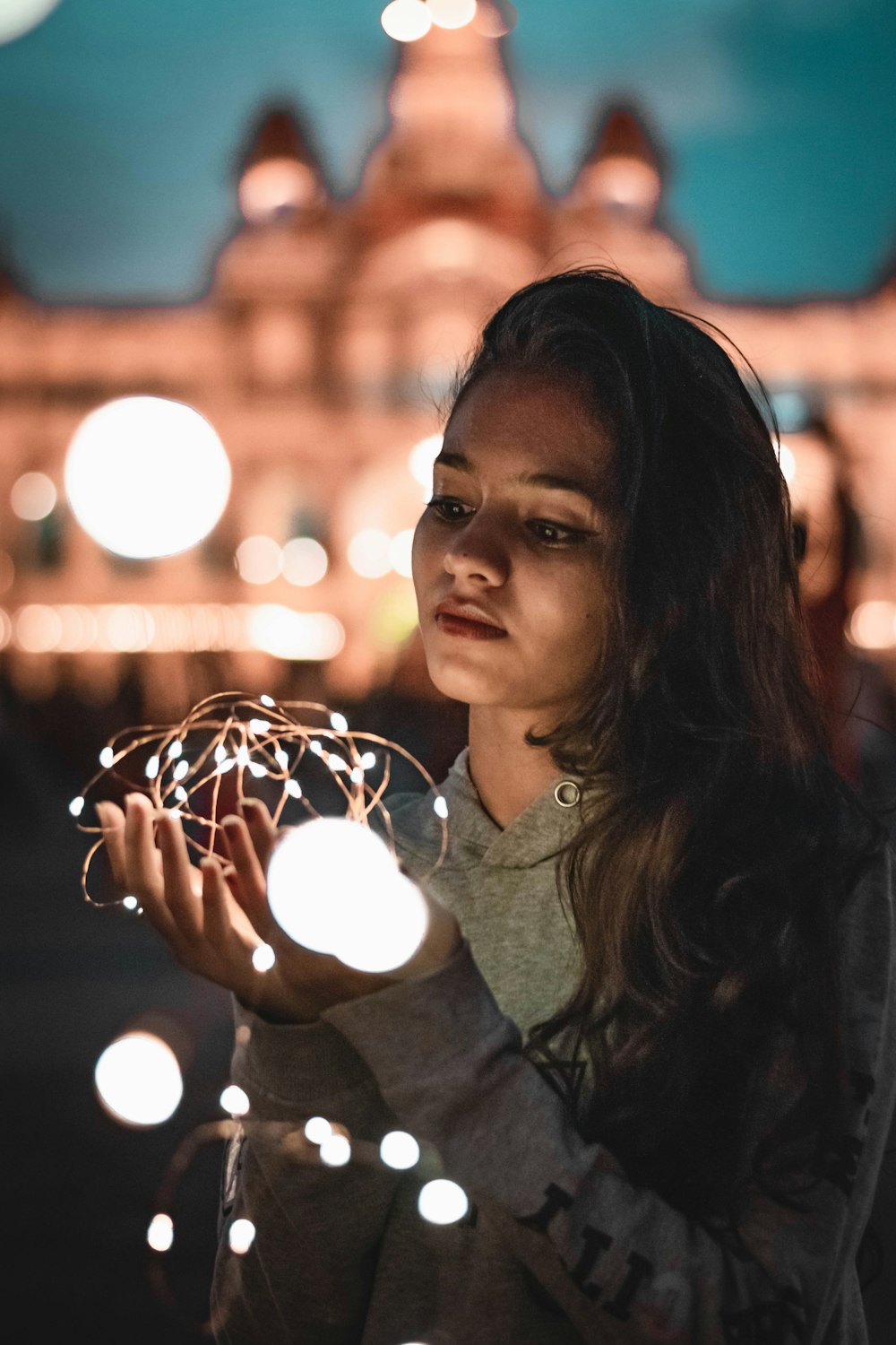 a woman holding a ball of lights in front of a building