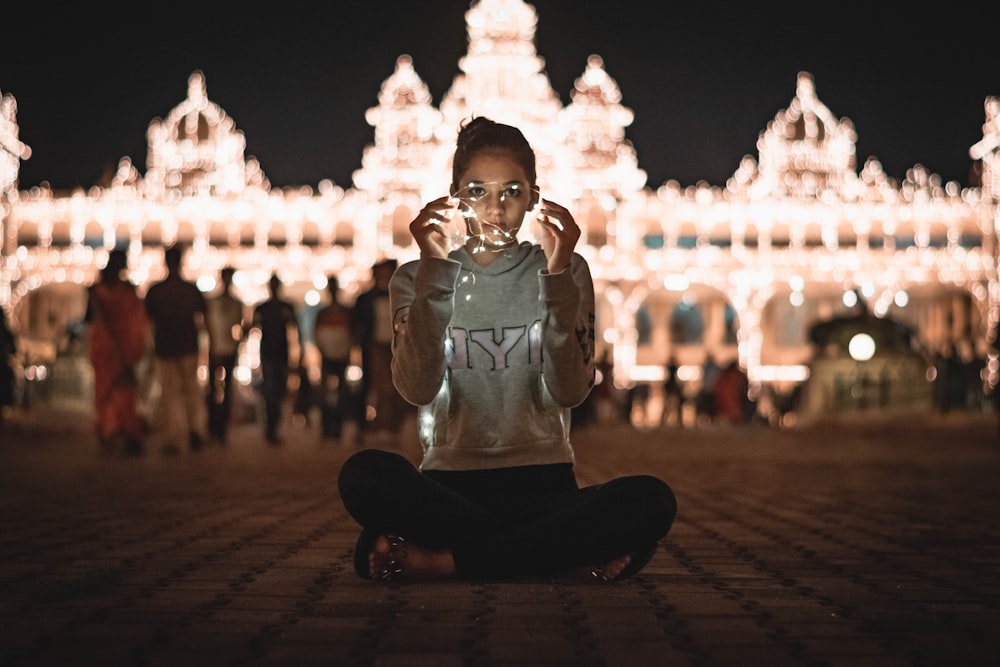 a woman sitting on the ground in front of a building