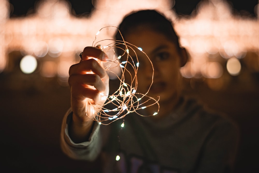 a woman holding a string of lights in her hand