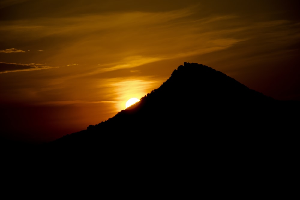 the sun is setting behind a mountain peak