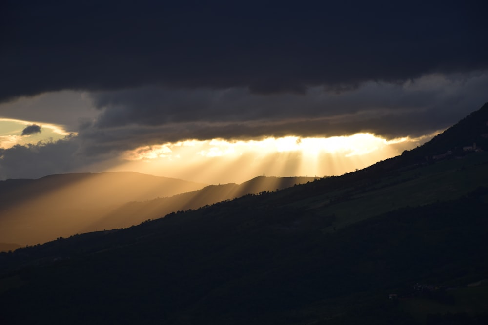 the sun is shining through the clouds over the mountains