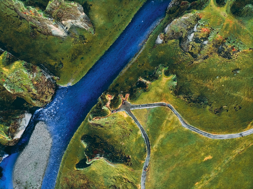 an aerial view of a river running through a lush green field