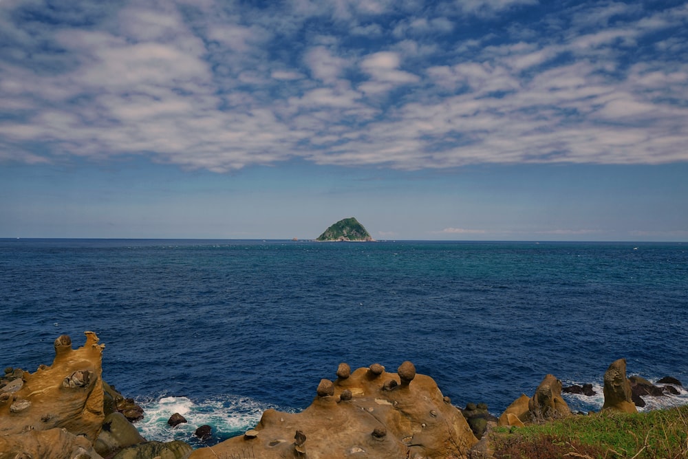 brown rocks on seashore under blue sky during daytime