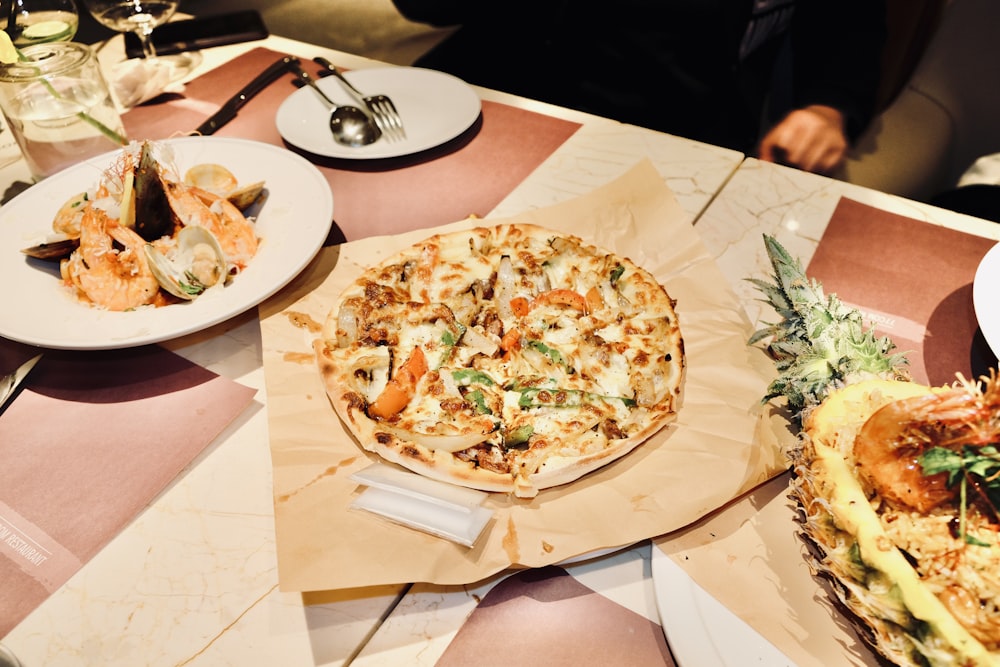 a table topped with plates of food and a pizza