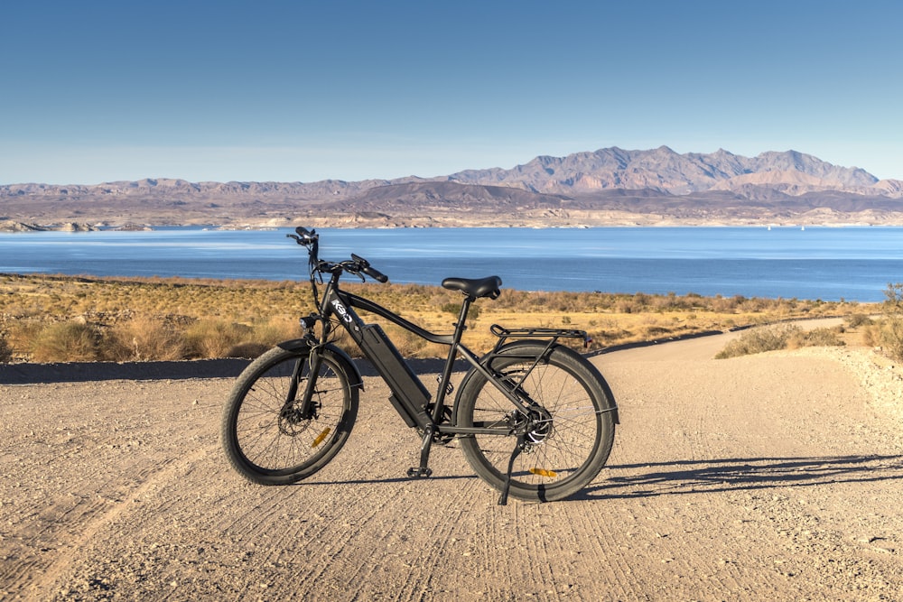 black and gray hardtail mountain bike on brown sand near body of water during daytime