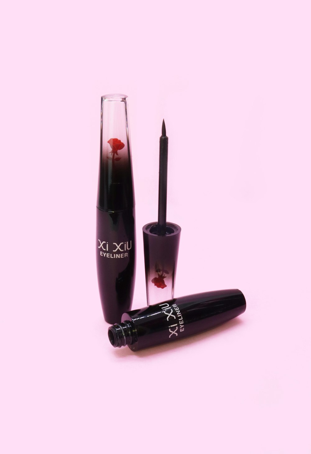 a mascara and a glass on a pink background
