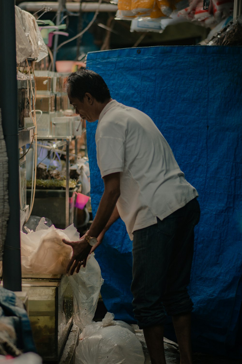 a man standing over a pile of bags