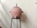 A large clay water storage pot with a metal lid is positioned on a black metal stand. The pot is equipped with a small tap at the bottom.