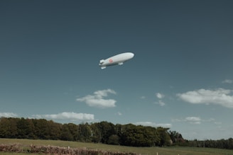 a large white balloon flying over a lush green field
