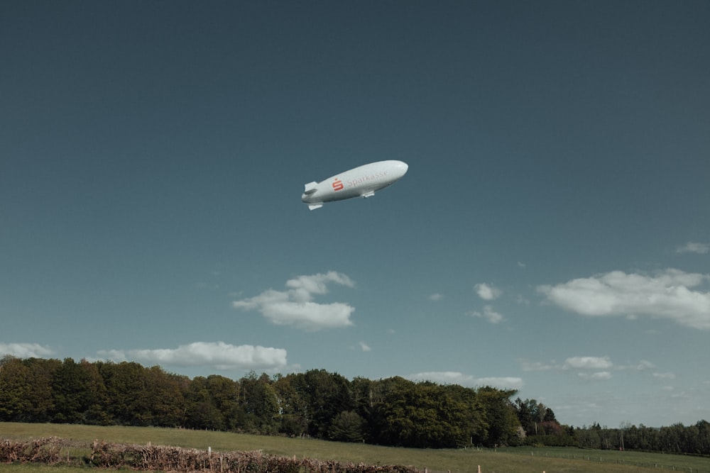 a large white balloon flying over a lush green field