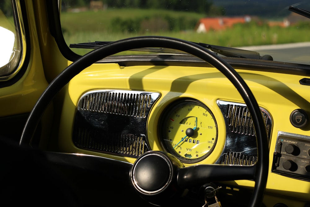 the dashboard of a yellow car on a country road