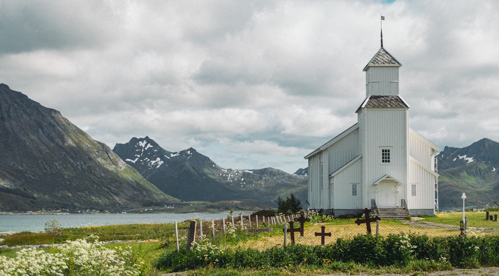 uma igreja branca com um campanário em uma colina gramada