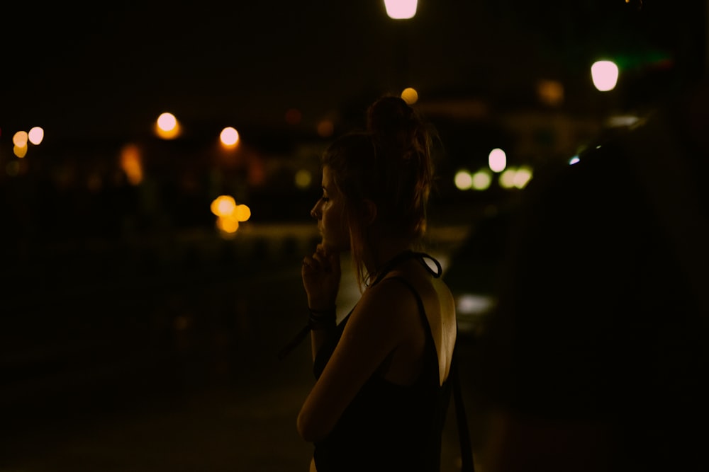 a woman standing in the dark talking on a cell phone