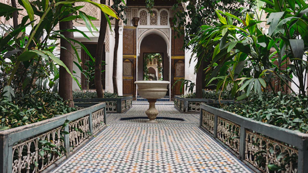 Sunlit courtyard terrace with intricate tilework and lush greenery at Riad La Samira.