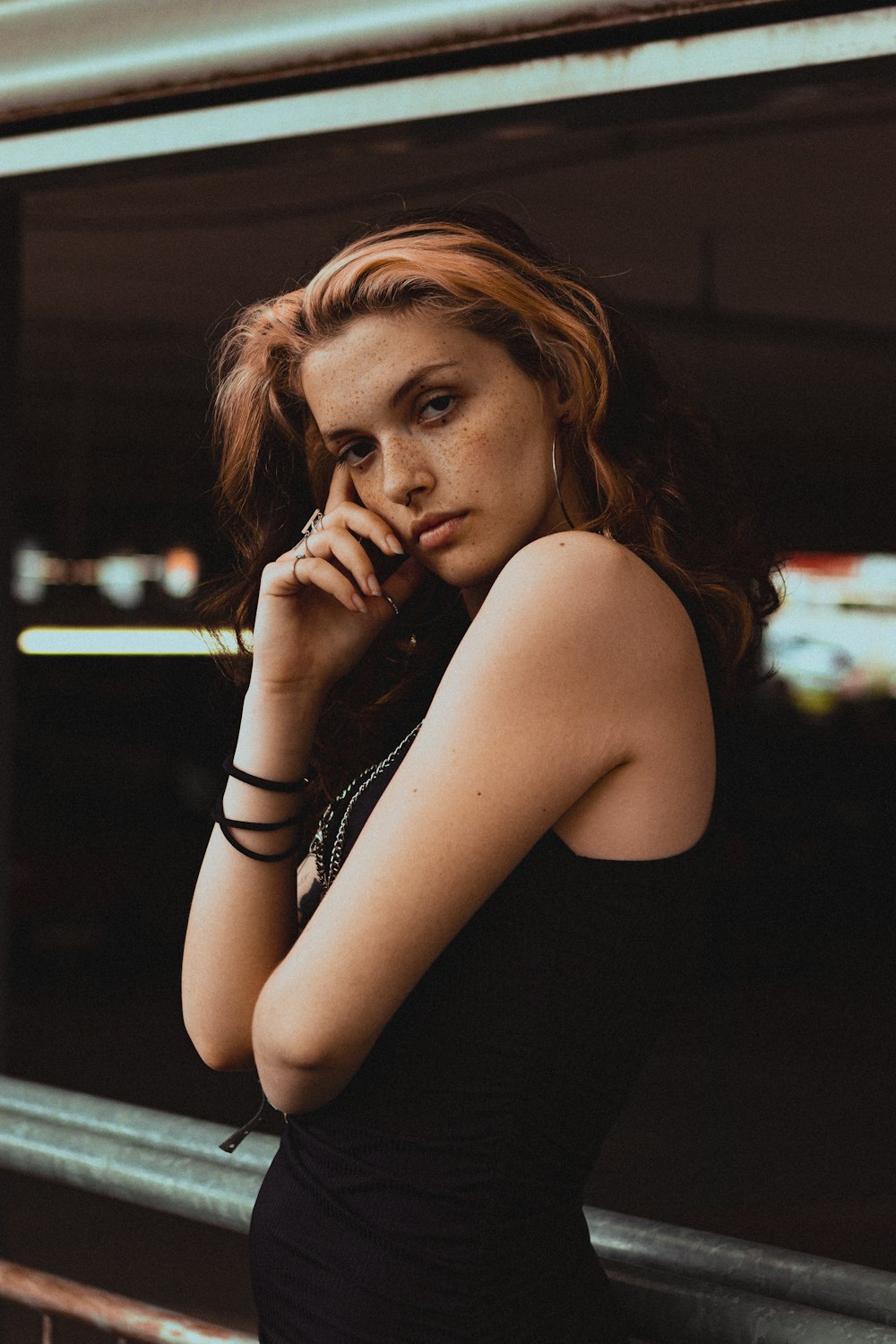 a woman in a black dress leaning against a wall