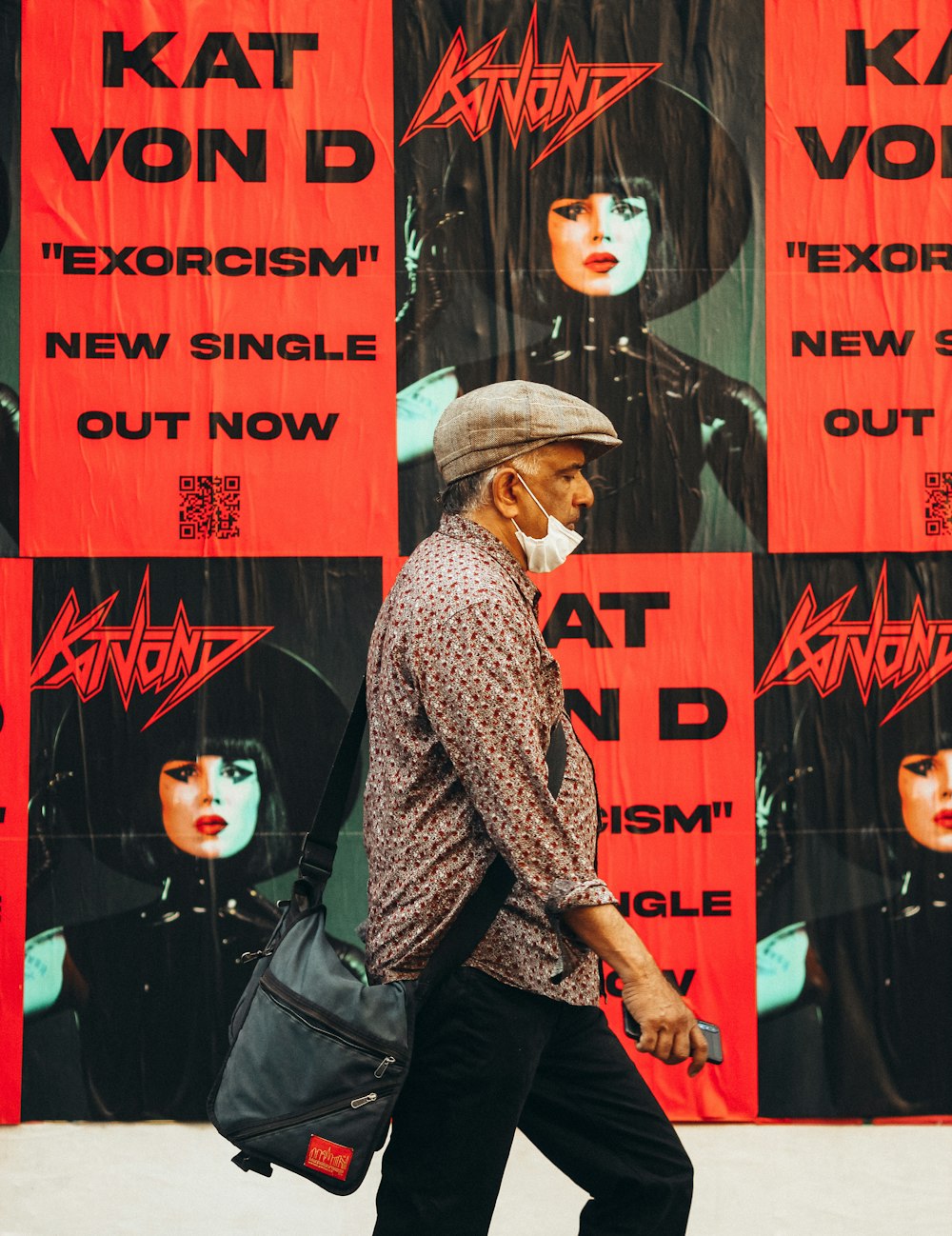 a man walking down the street in front of a poster