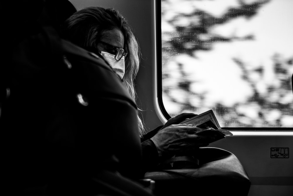 a woman sitting on a train reading a book