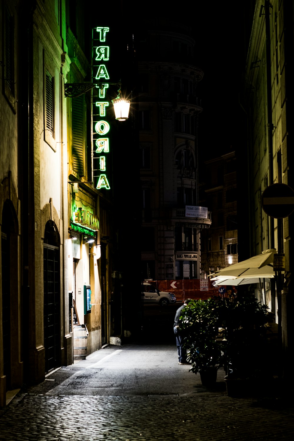 a dark alley way with a neon sign on the side of it