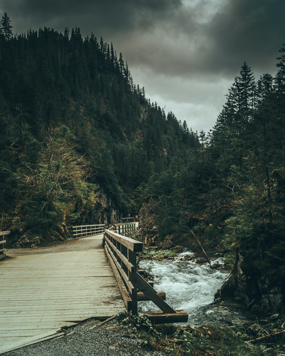 a wooden bridge over a rushing river in a forest
