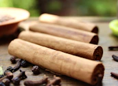 A neat arrangement of Indonesian spices like cinnamon sticks, cloves, and nutmeg on a rustic wooden table.