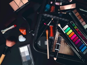 a variety of cosmetics and makeup brushes on a table