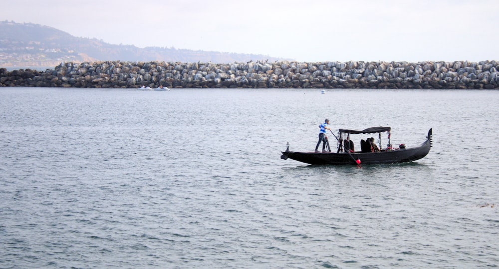 a man standing on the back of a boat in the water
