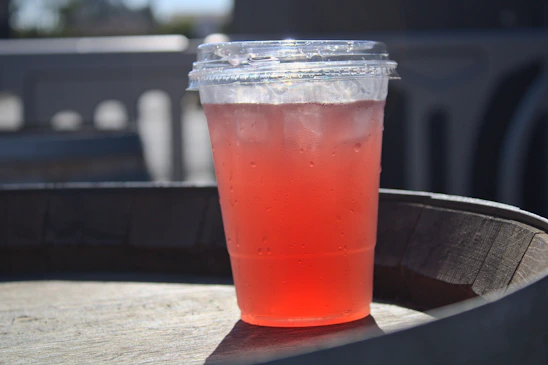 A sleek Frostveil Cool.Me cup insulator snugly wrapped around a frosty glass on a sunny patio.