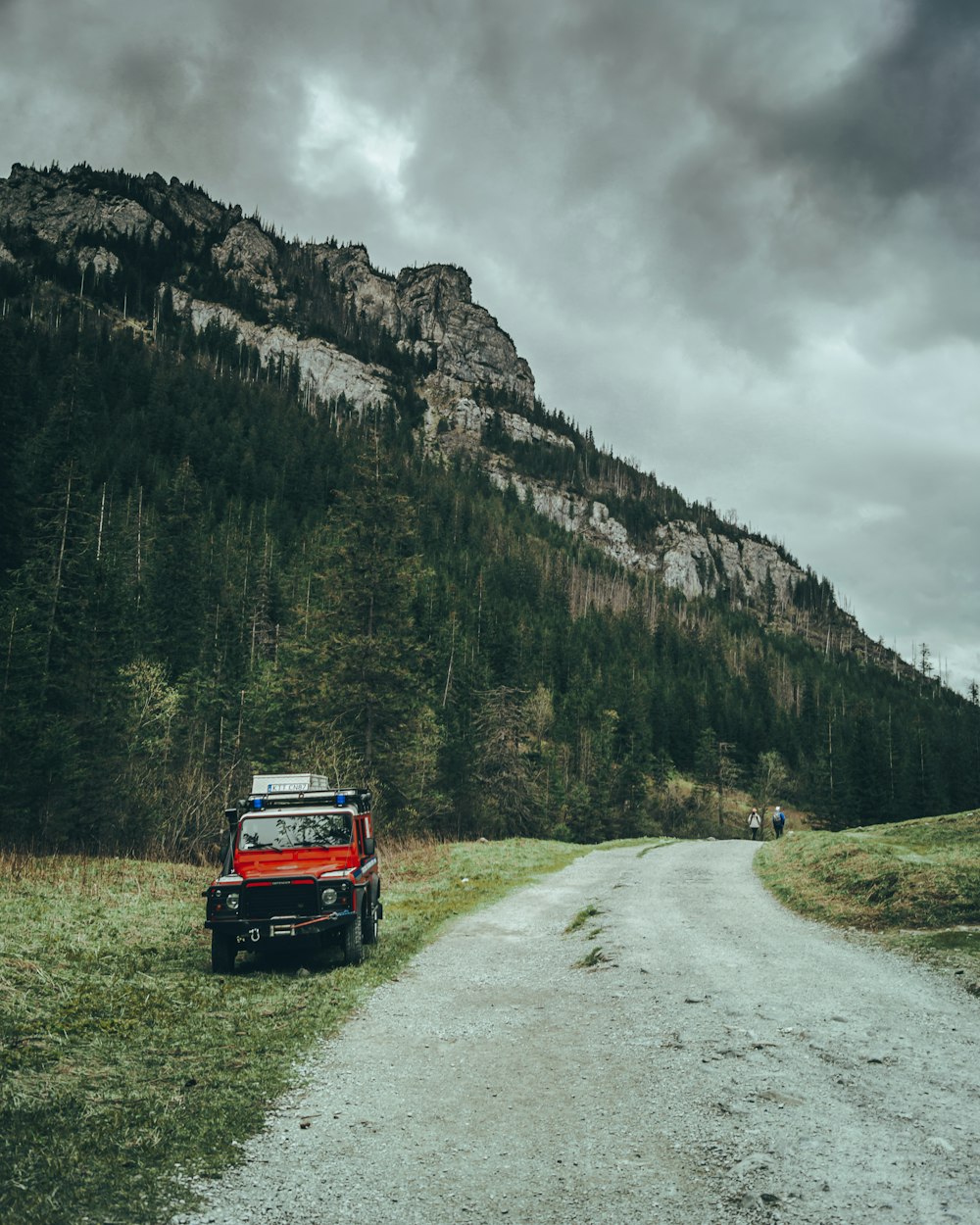 a red truck parked on the side of a dirt road