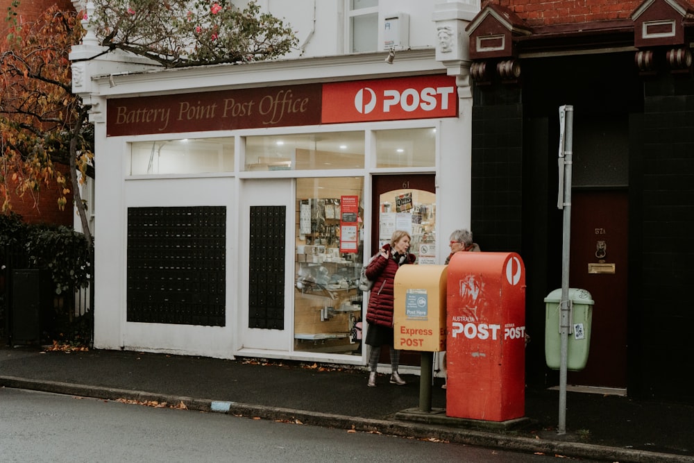 man in black jacket standing near red coca cola trash bin