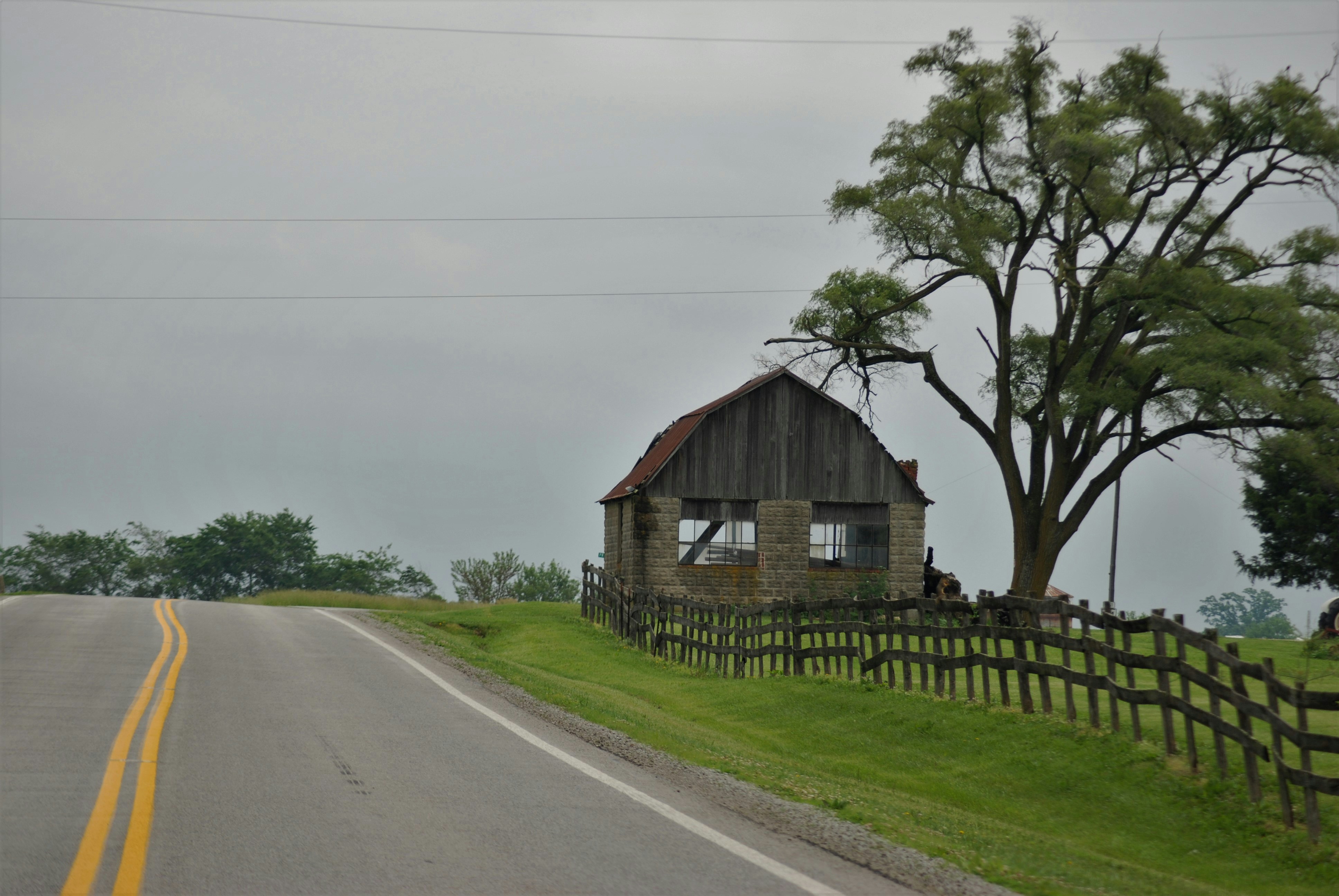 an old barn sitting on the side of a road