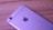 A smartphone with a metallic finish is placed on a wooden surface. The phone's back features a camera, a flash, and a well-known logo.