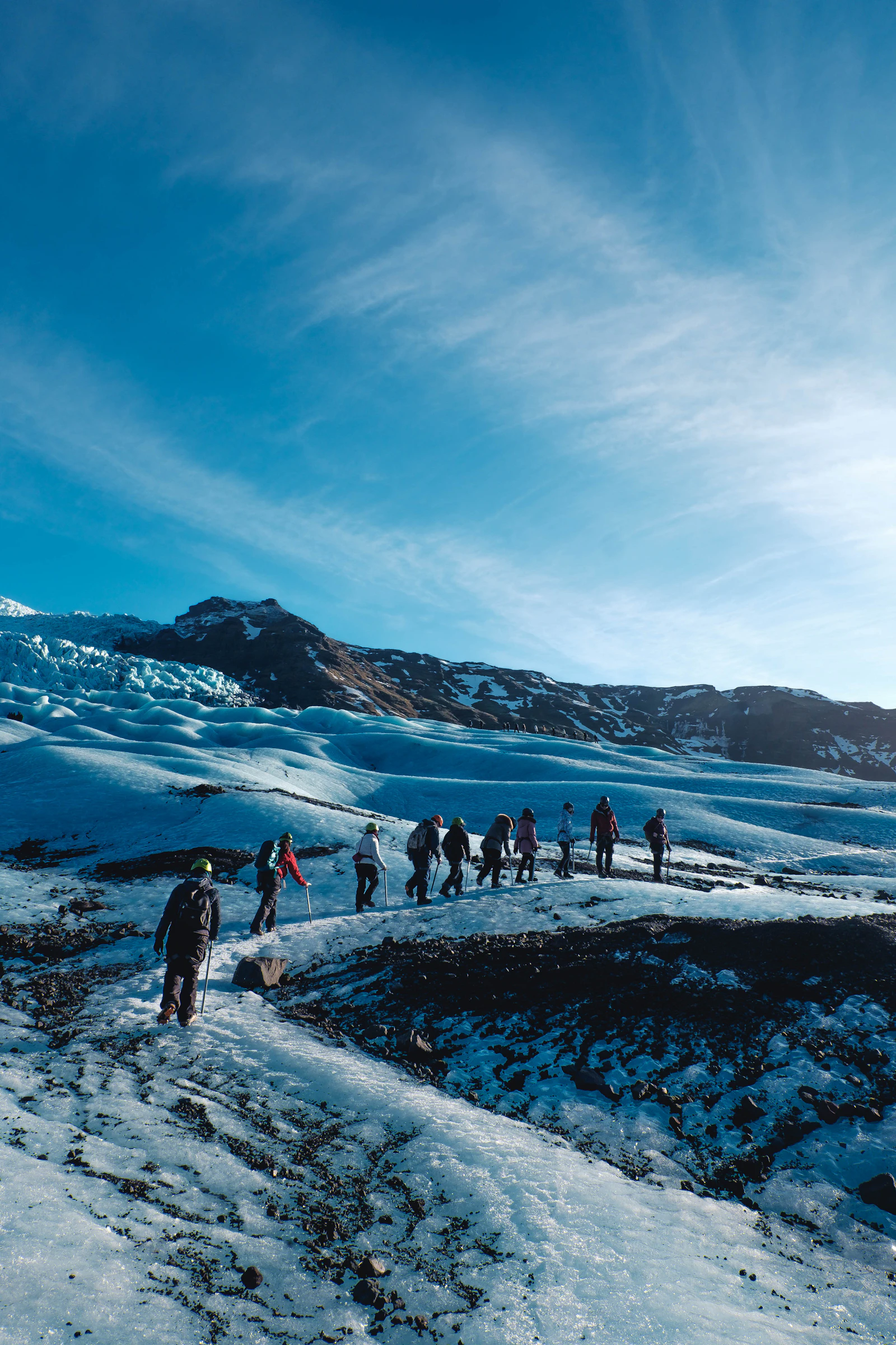 Small guided group walking single file across blue glacier ice