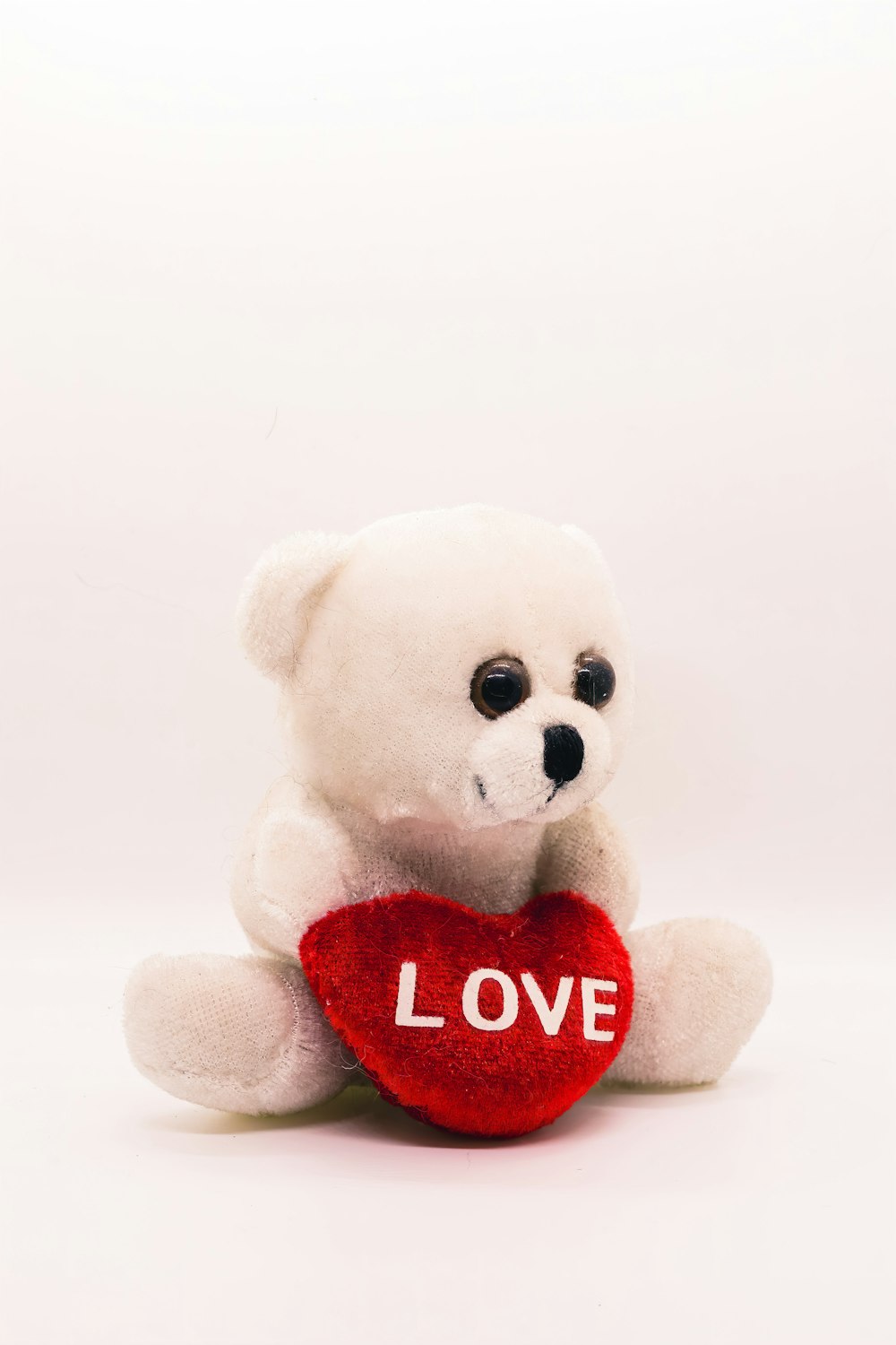 a white teddy bear holding a red heart