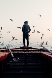 a man standing on top of a boat surrounded by seagulls