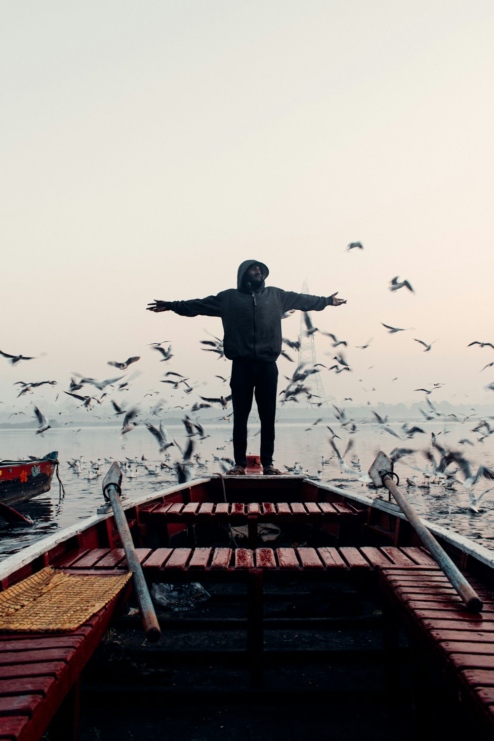 Un uomo in piedi sulla cima di una barca circondato da uccelli