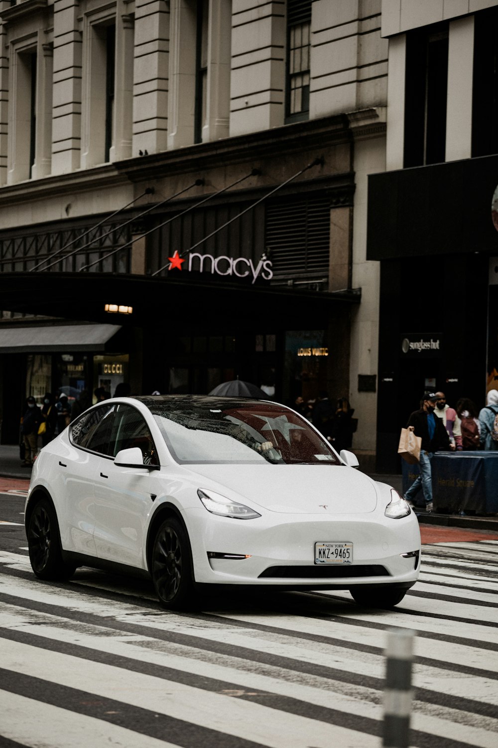 a white car driving down a street next to a tall building