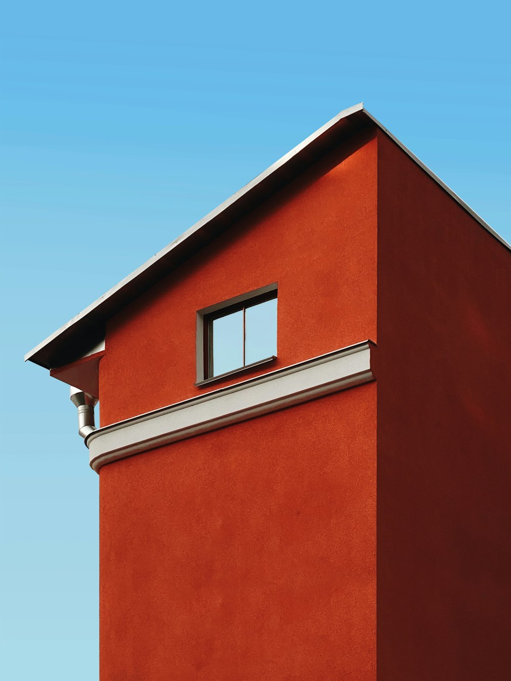 a red building with a window and a sky background