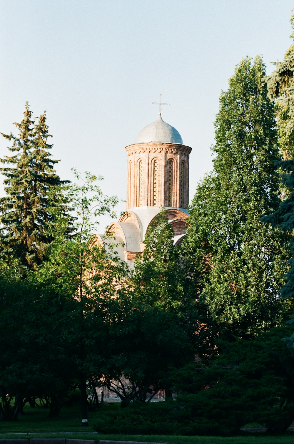 une église avec un clocher entouré d’arbres