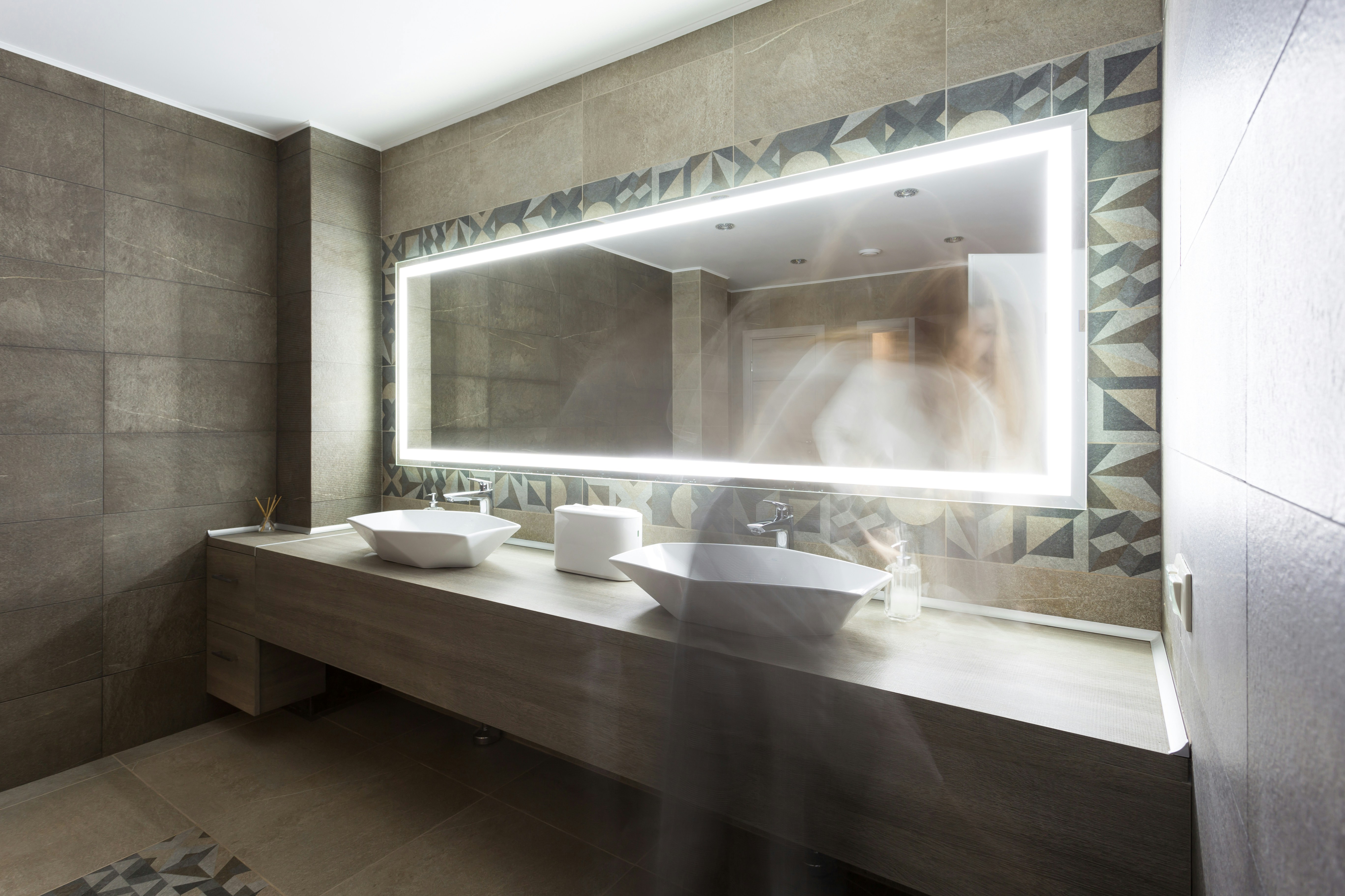 The washroom has a modern design. Against the background of a woman washes her hands
