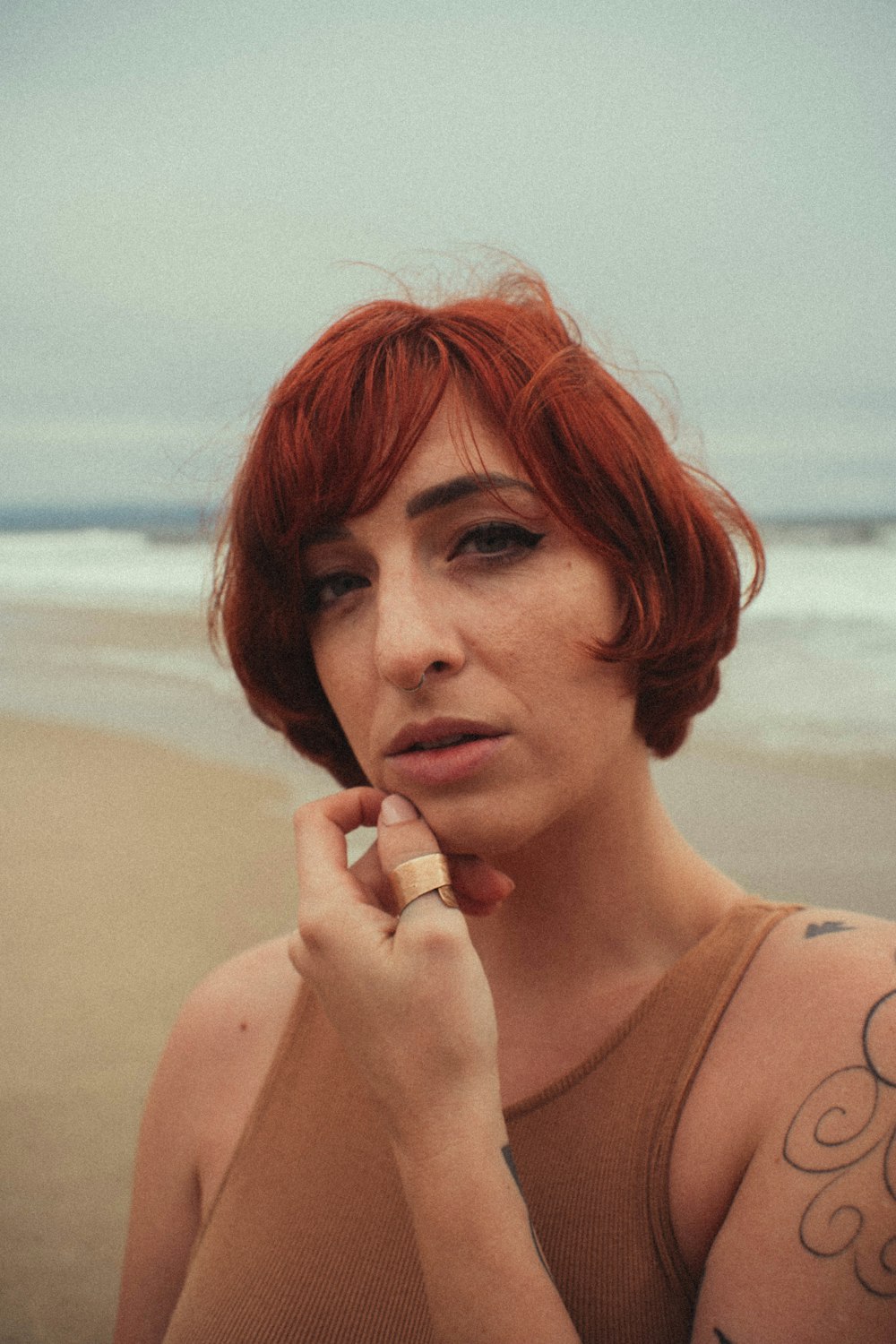 a woman with red hair smoking a cigarette on the beach