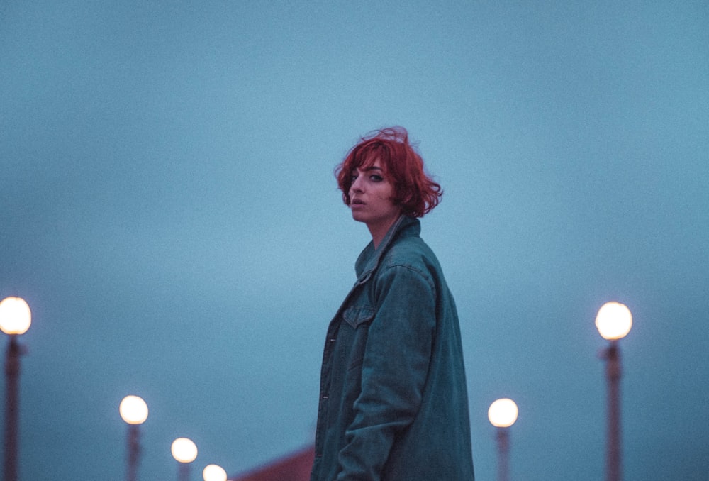 a woman with red hair standing in front of street lights