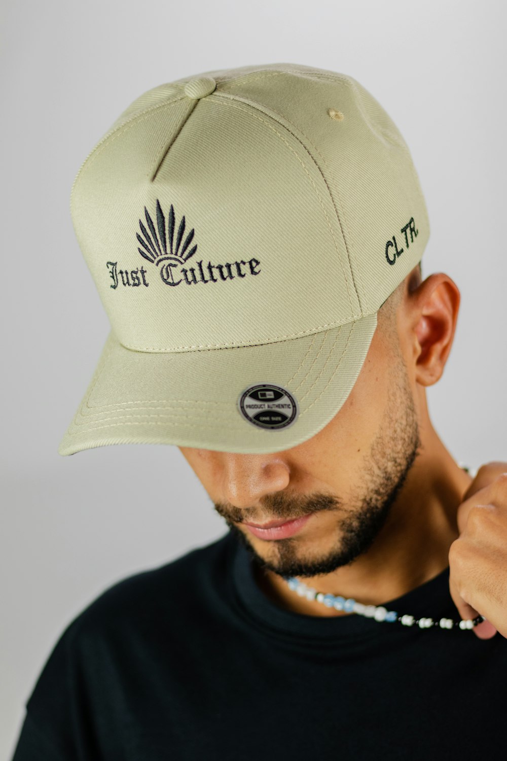 a man wearing a hat with the first culture embroidered on it