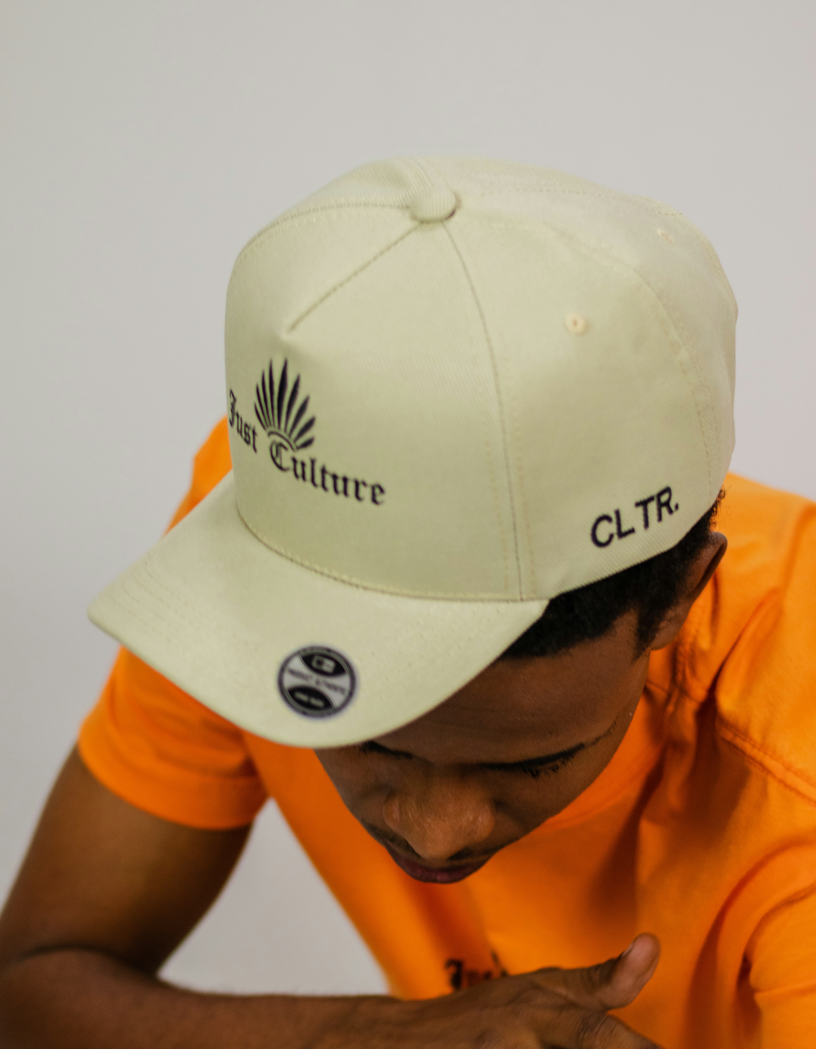 um homem vestindo uma camisa laranja e um chapéu branco