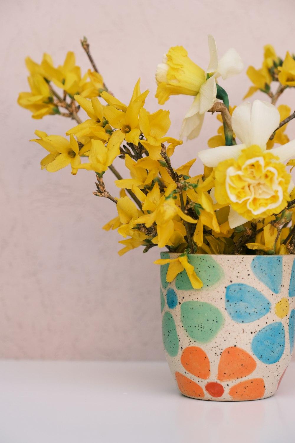 a vase with yellow and white flowers in it