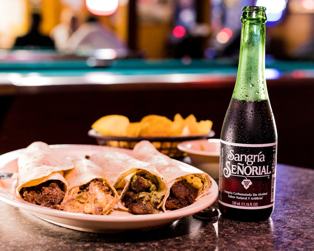 a plate of food and a bottle of beer on a table